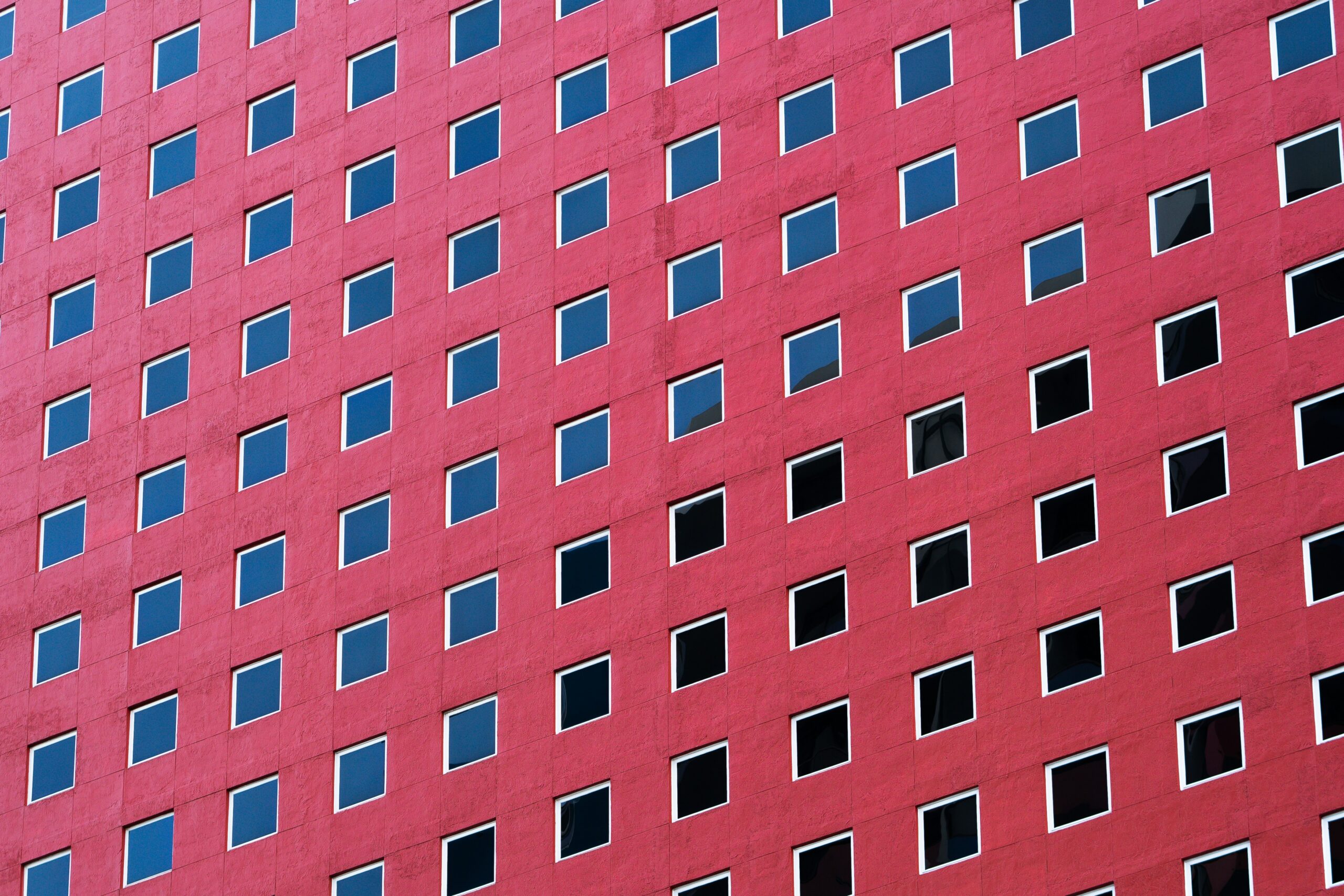 windows on a tall, red building seen from the street